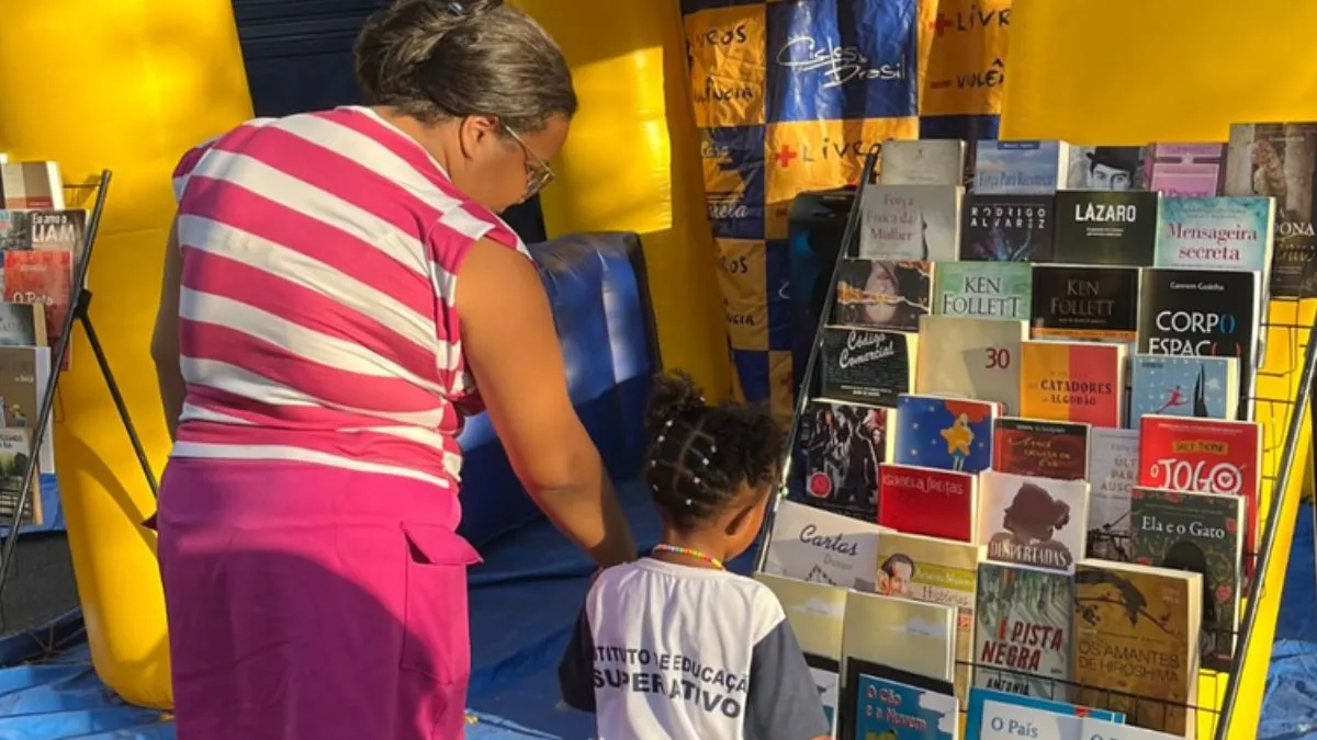 foto de uma senhora e uma criança olhando uma estante de livros