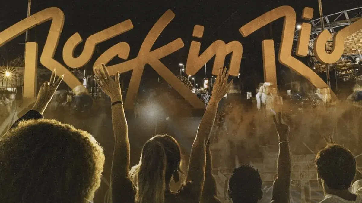 Foto do Rock in Rio. Pessoas de braços levantados com o nome do evento ao fundo