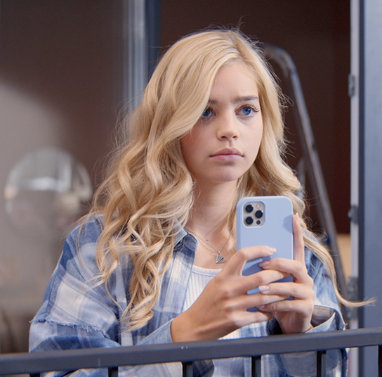 foto de uma menina loira de olhos azuis com um telefone na mão. Imagem do filme Coração Partido