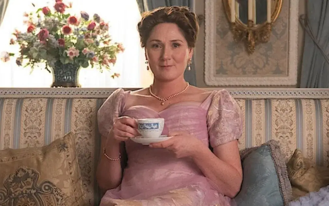 Violet Bridgerton sentada com uma xícaracde chá nas mãos e olhando pra frente